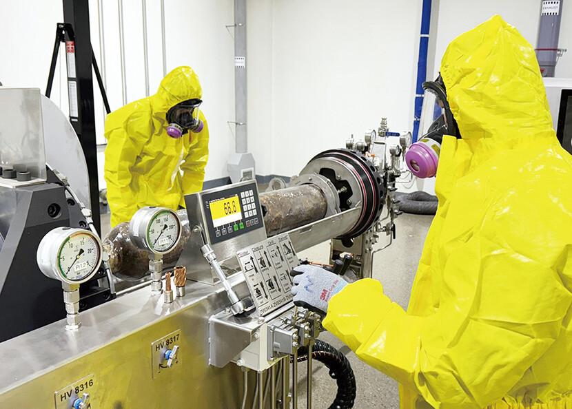 방호복을 입은 작업자들이 비정상용기에 천공작업을 하고 있다.